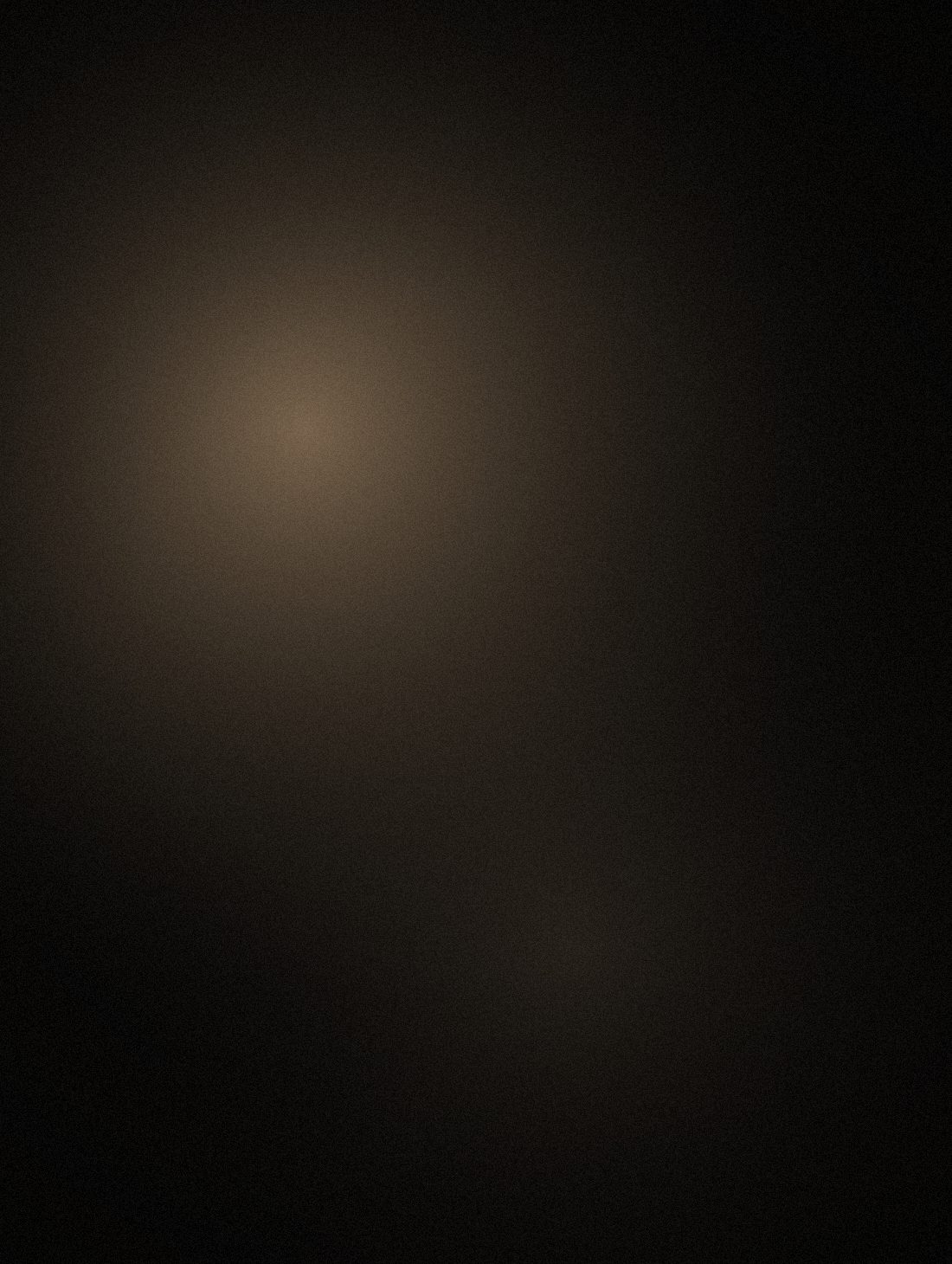 Seated man emerging from black, lit by a single key light from the left